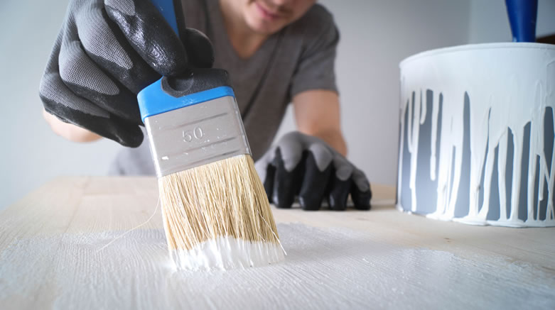 Close up of paint brush being used to paint surface white